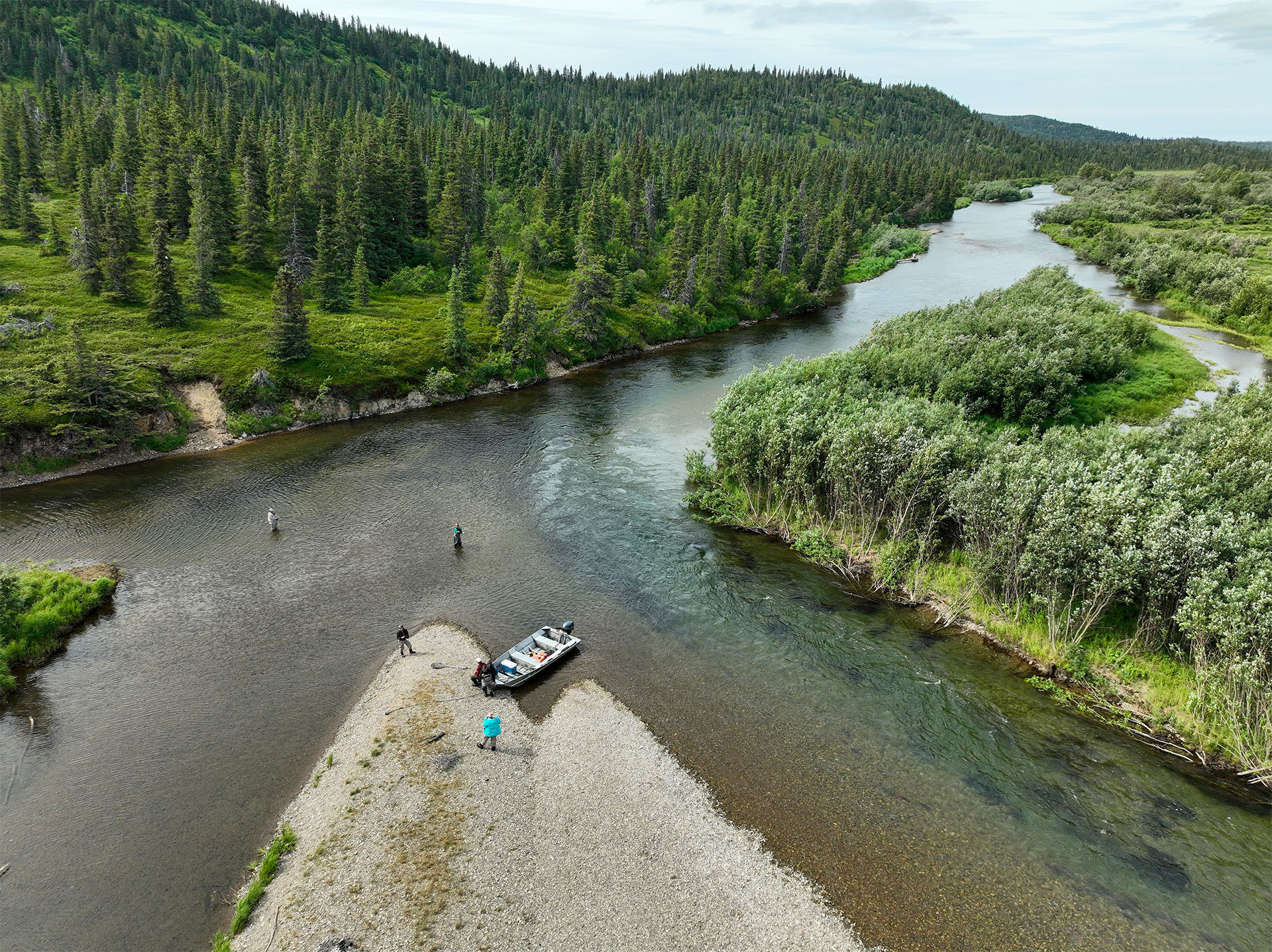 Overhead drone view of a boat and anglers on a gravel bar in an Alaska river