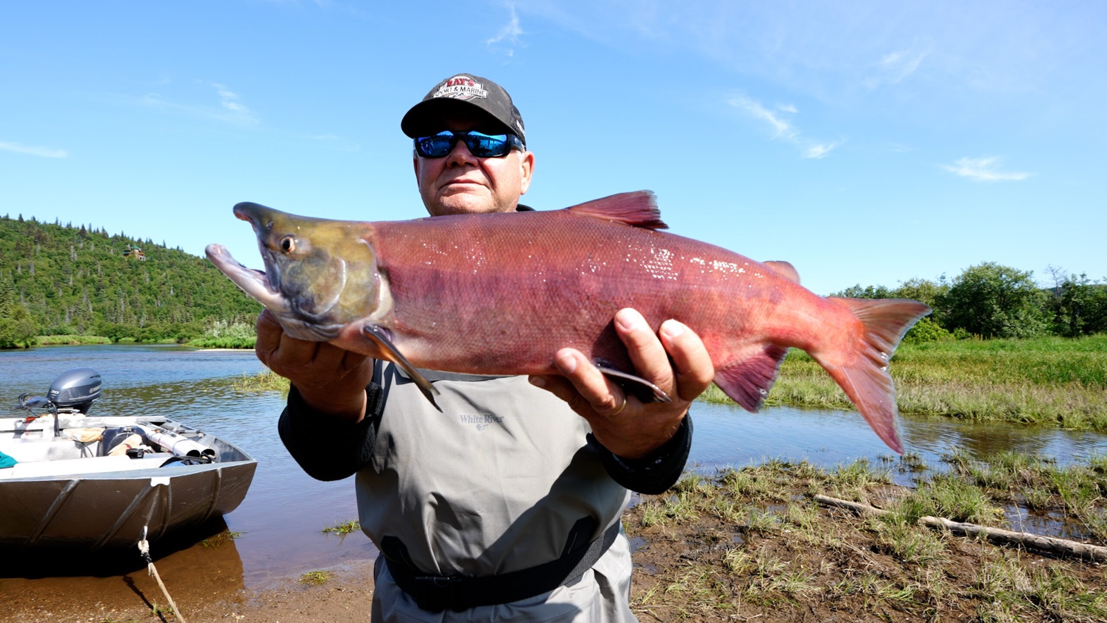 Guest holding a large sockeye salmon beside the boat